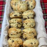 Fruit scones in long wicker basket, with white lining, tartan background.