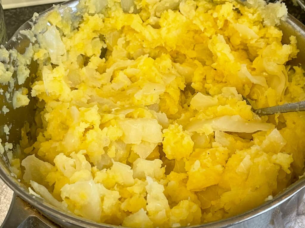 cabbage, potato, and turnip cooked, mashed and mixed together in the saucepan.