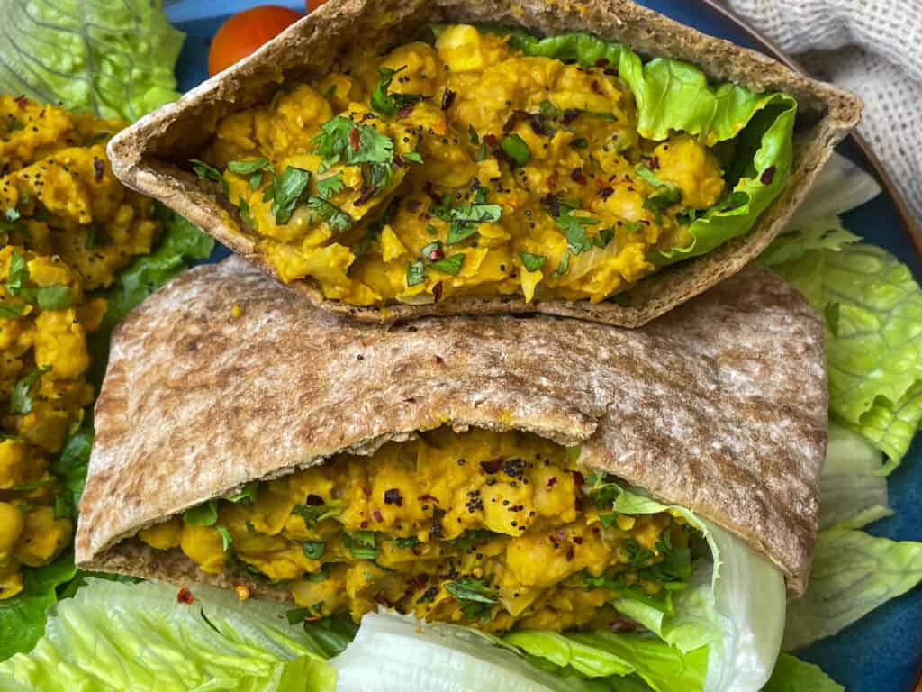 2 wholemeal pitta breads packed with chickpea scramble, one bread on top of the other, lettuce scattered around.