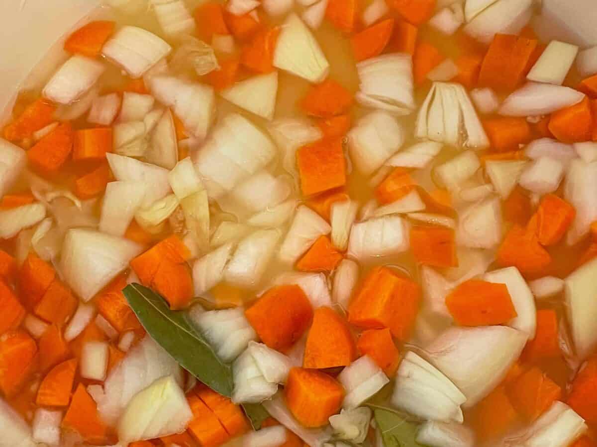 Carrot, onion and bay leaf added to soup pot.