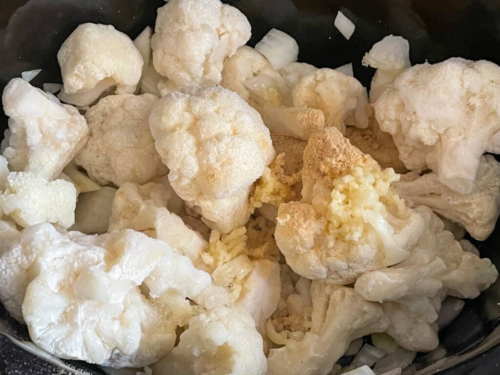 Cauliflower, onion, garlic and ginger powder added to slow cooker.