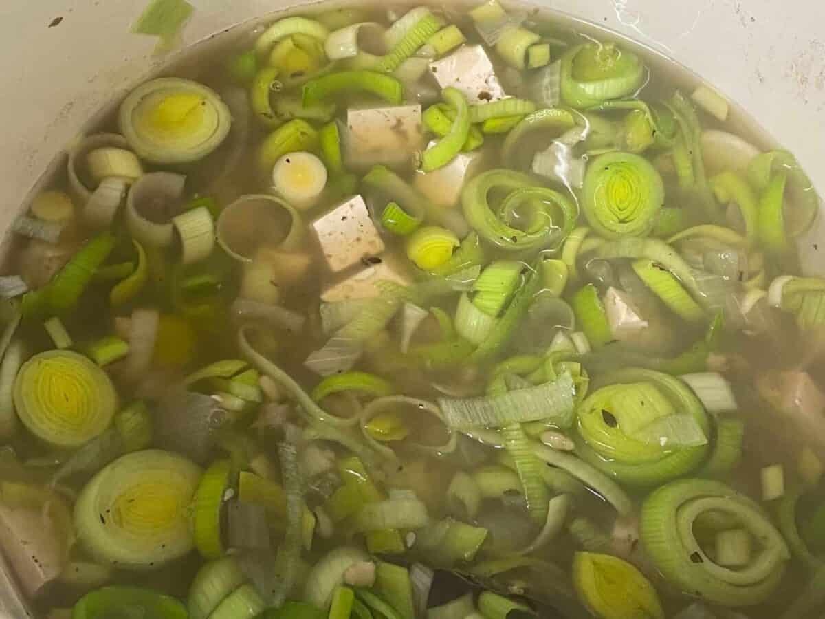 Leeks and tofu added to the soup pan.