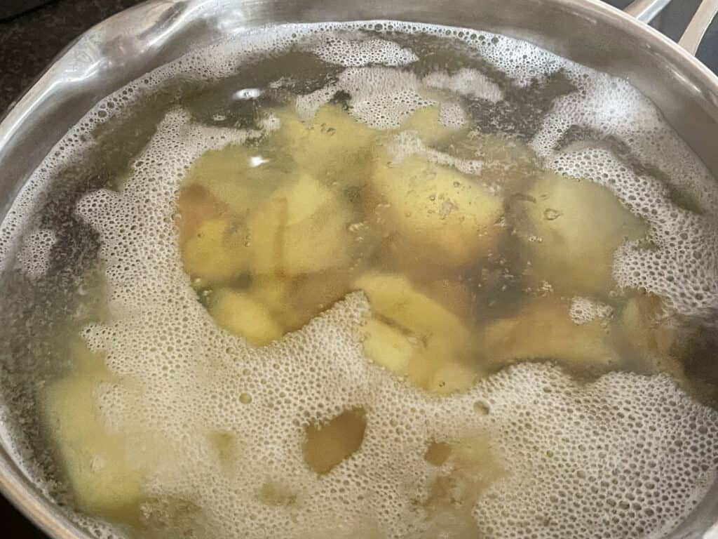 Potatoes cooking in silver pan.