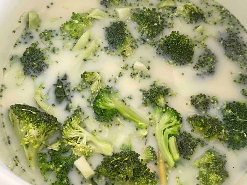 Plant -based milk poured into pot with pasta and broccoli.