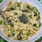 Quick vegan cheesy pasta served in white bowl with green flower background, featured image.