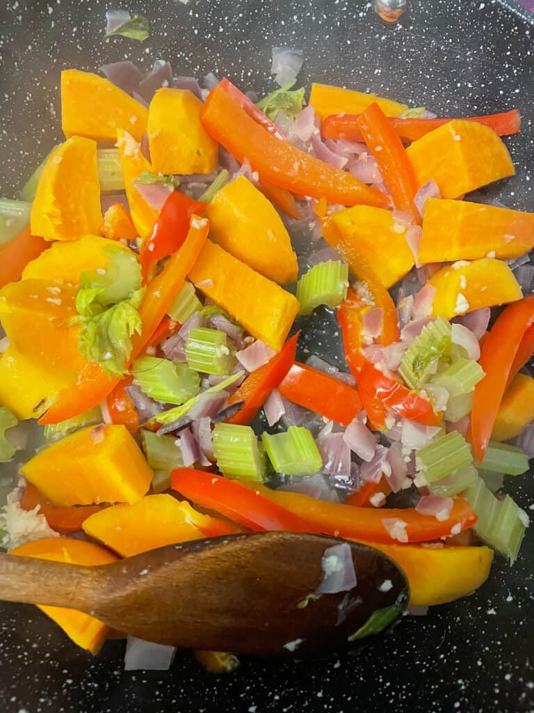 veggies cooking in the skillet with wooden spoon.