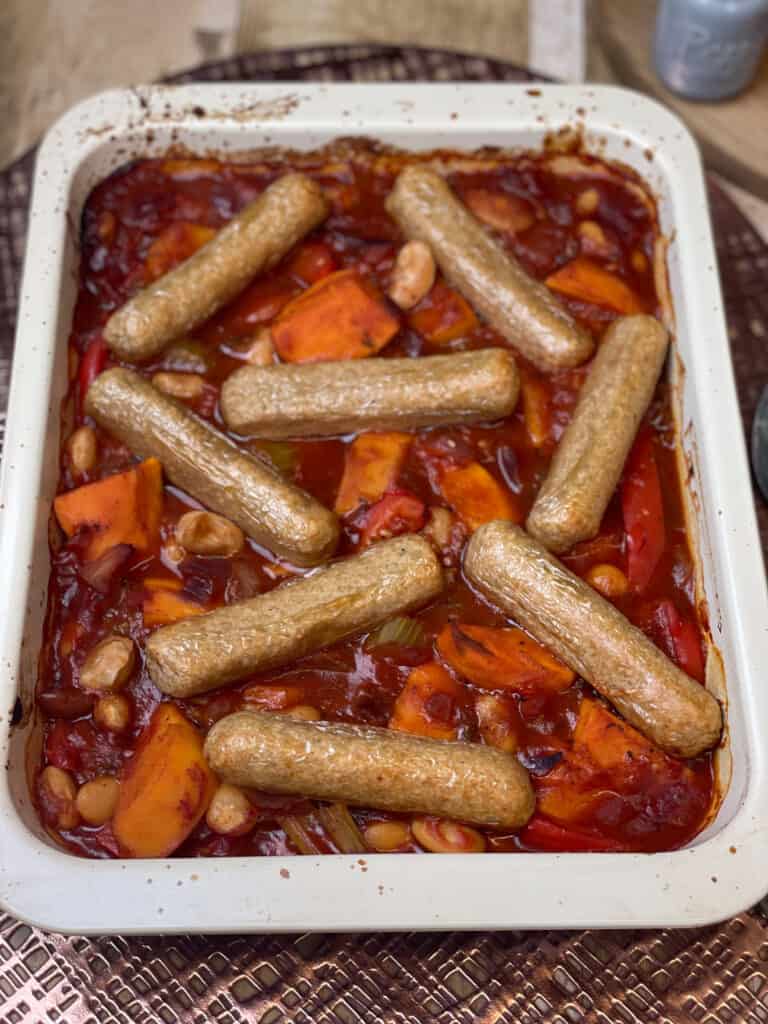 Sausage casserole baked and ready to serve, on a wire rack with brown metallic mat underneath.