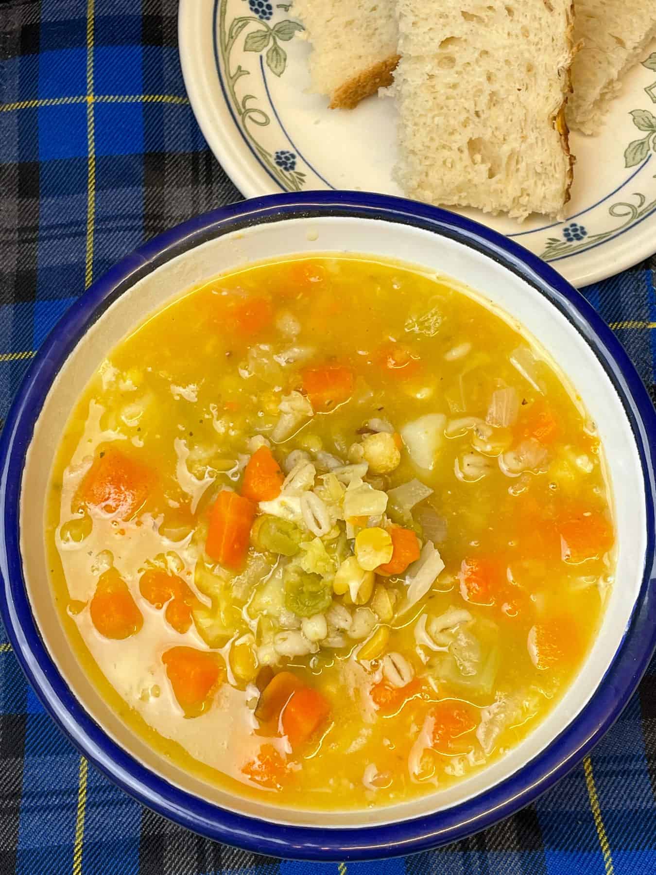 A close up image of a bowl of vegan Scotch broth, with no garnish, with bread to side.