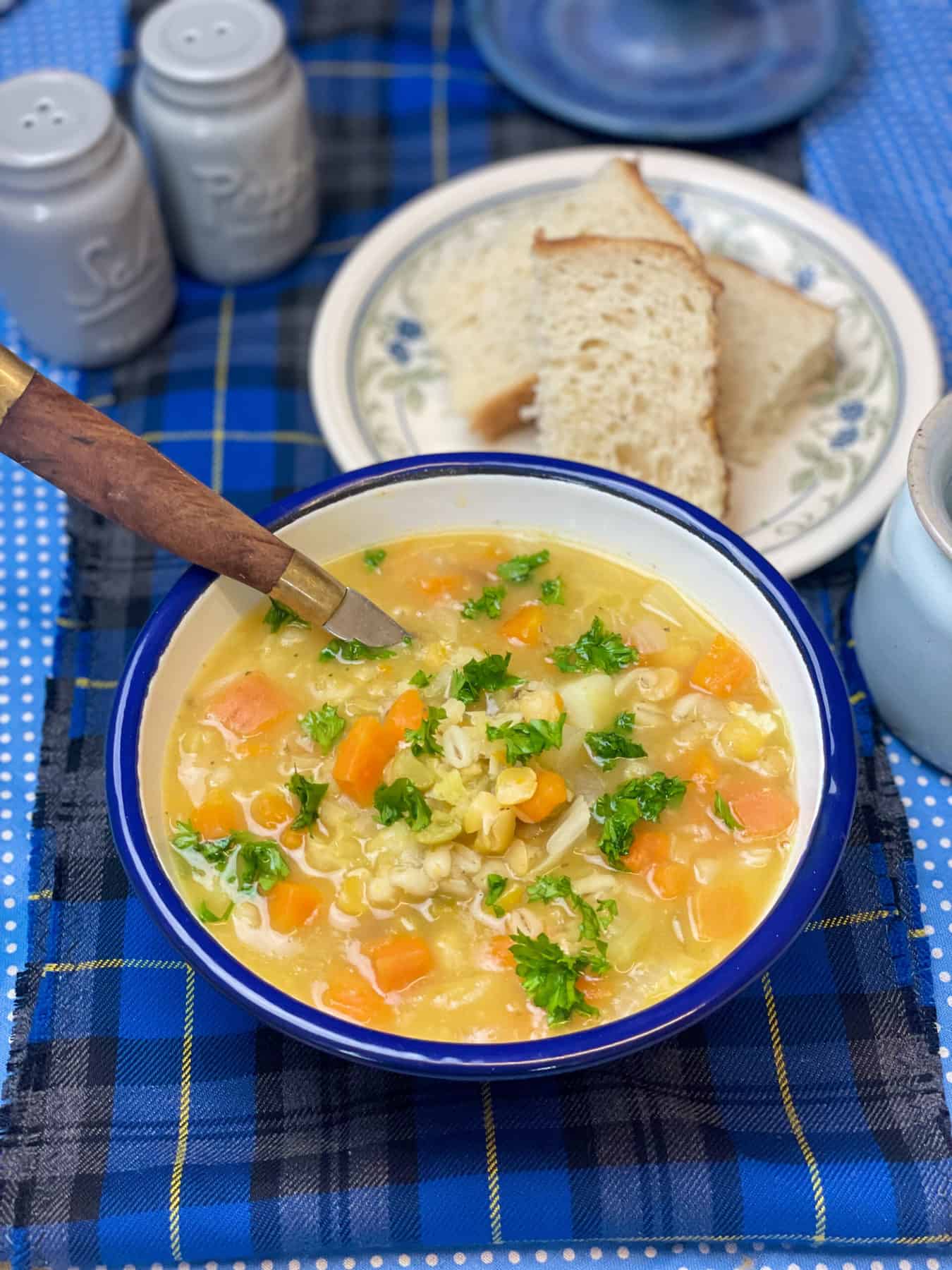 Soup served with crusty bread and chopped parsley, blue tartan background.