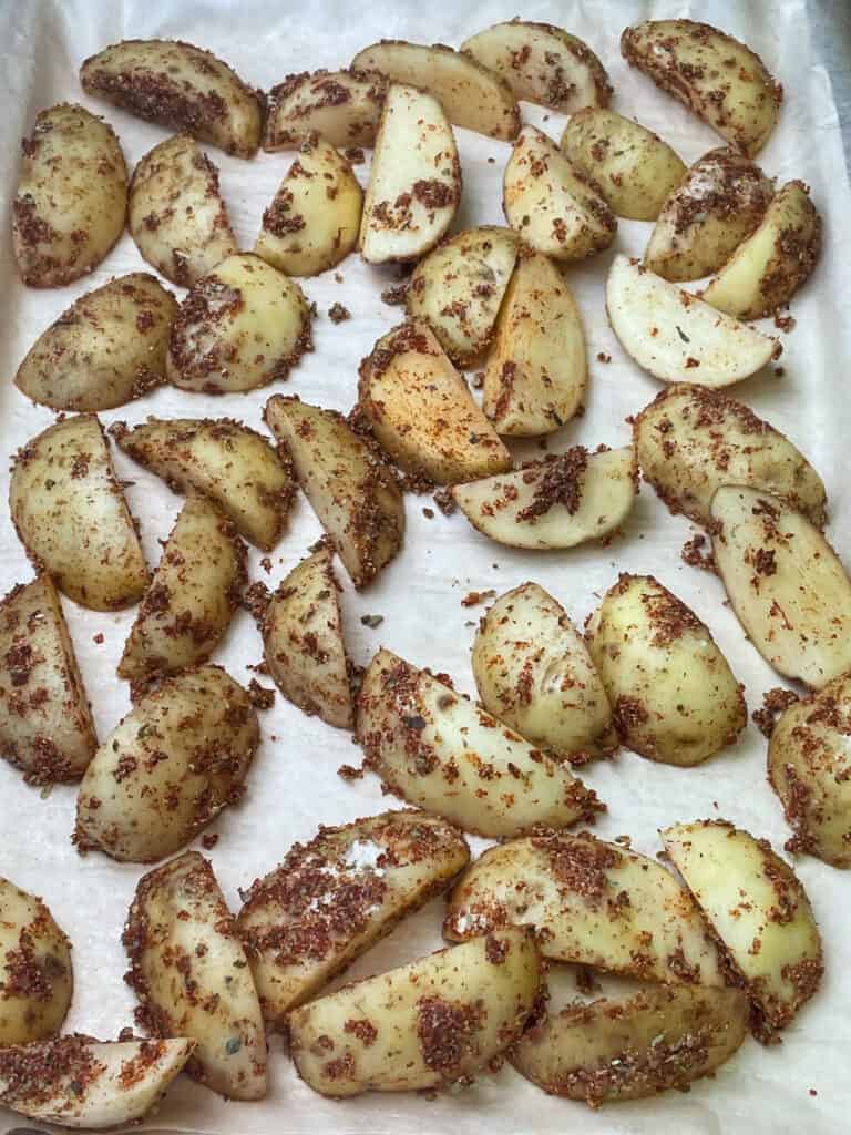 Uncooked potato wedges on baking tray.