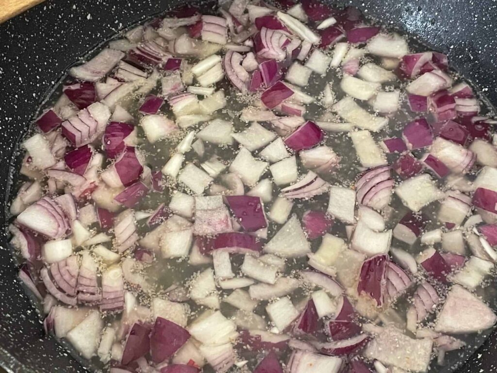 red onion cooking in black sillet.