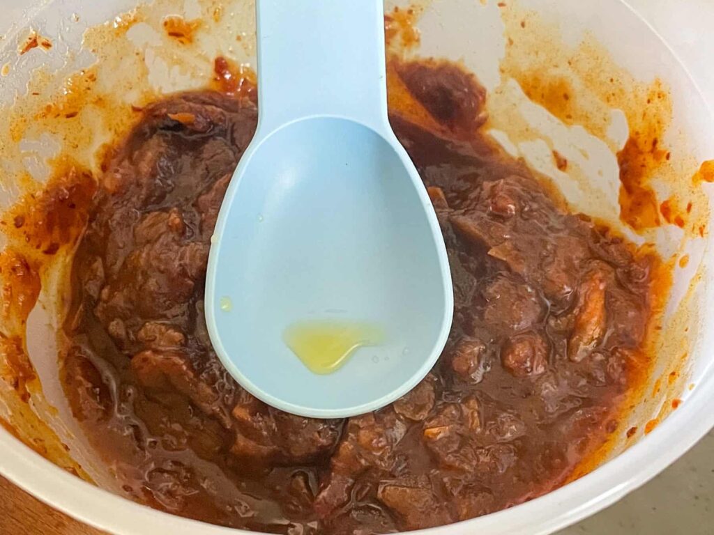mashed dates in small bowl with tablespoon with a drop of orange juice.