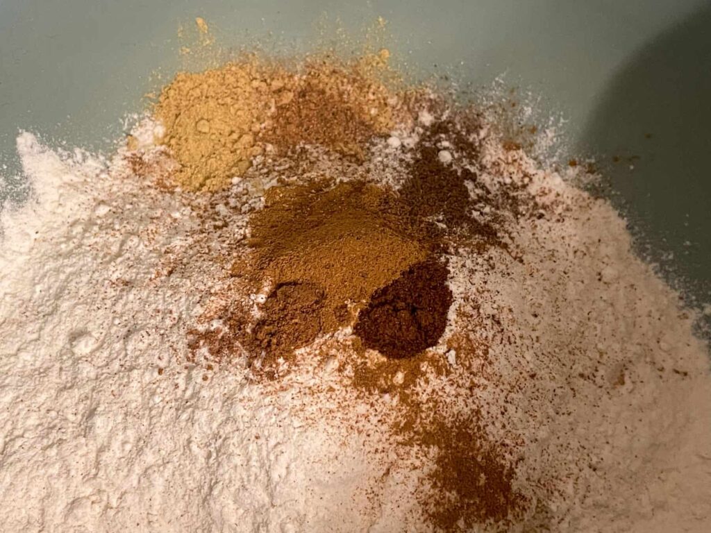 Pumpkin spices added to flour in turquoise mixing bowl.