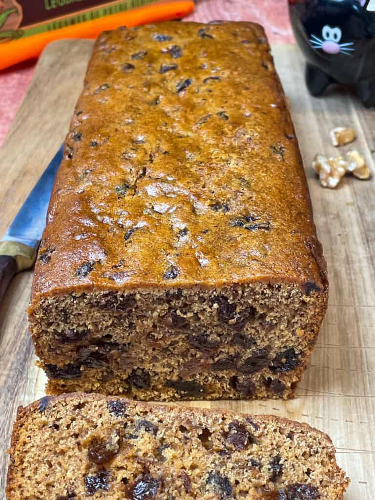 Close up of vegan pumpkin spice fruit cake with one slice and cake knife.