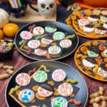 Black plates filled with vegan peppermint screams, pumpkins in background, Halloween napkins and plates.