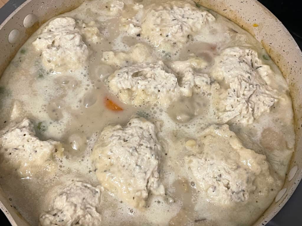 uncooked dumplings added to stew in pan.