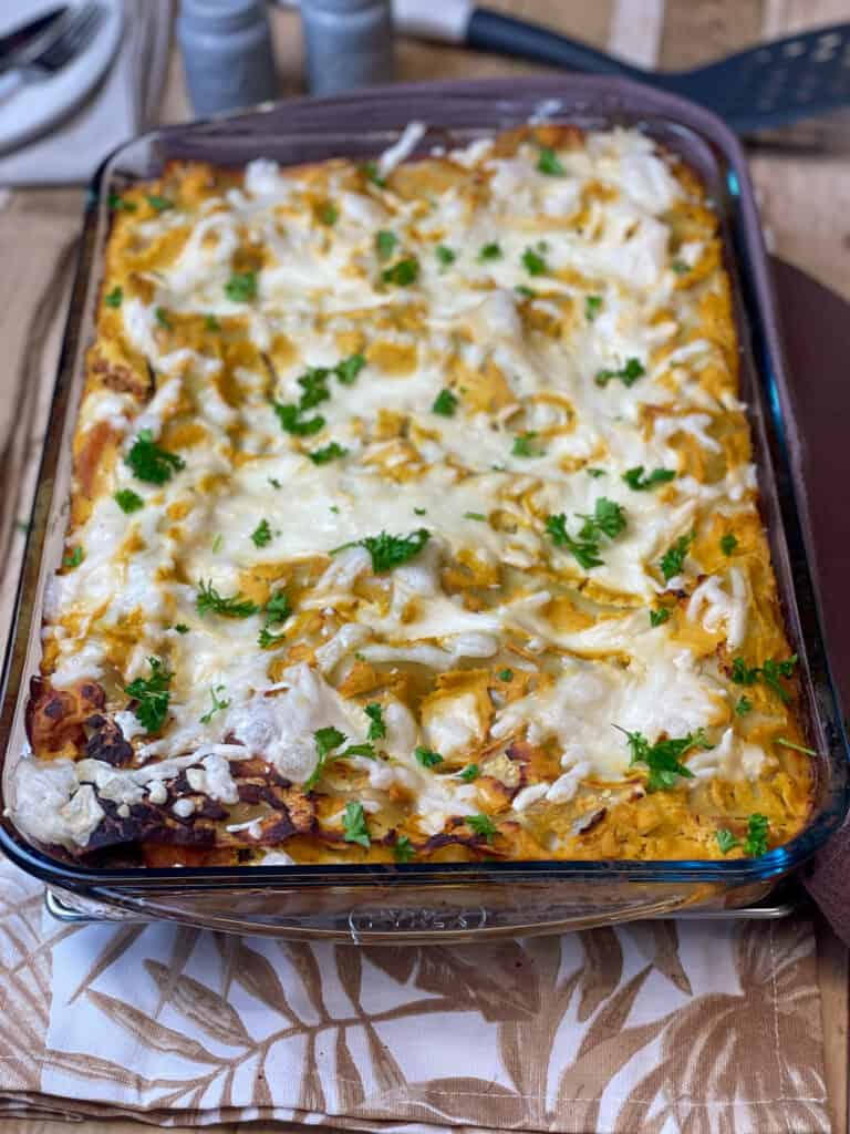 Close up of lasagna in the glass rectangular baking dish, tan and white background.