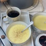 Featured image, tray with semolina pudding and mug of tea, nutmeg and zester to side, saucepan with semolina to back, jam pot to side and second bowl of pudding to side.