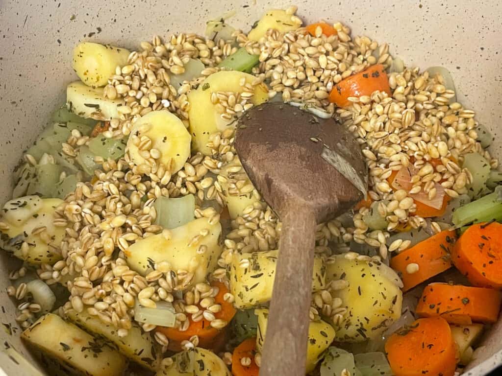 Barley mixed through the veggies in pan with wooden spoon.