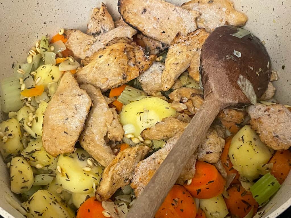 meat-free pieces mixed through barley and veggies in pan, with wooden spoon.