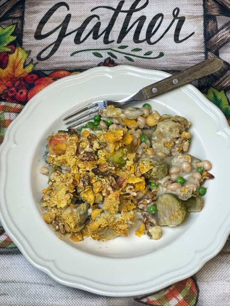 Featured image for vegan vegetables au gratin, close up of scalloped bowl of au gratin with wooden handled fork, and tea towel with the word 'gather'.