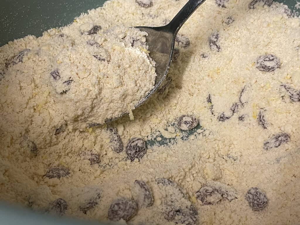all ingredients for rock cakes mixed together in bowl with spoon.