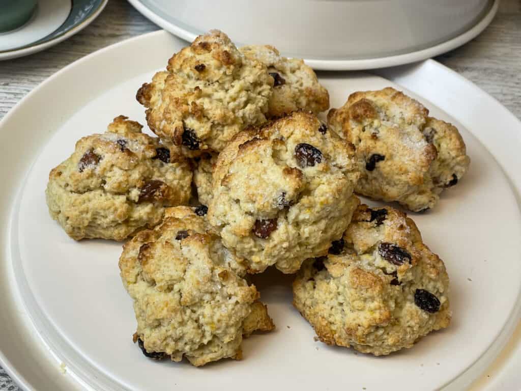 pile of vegan traditional British rock cakes on cake tray with lid to side.
