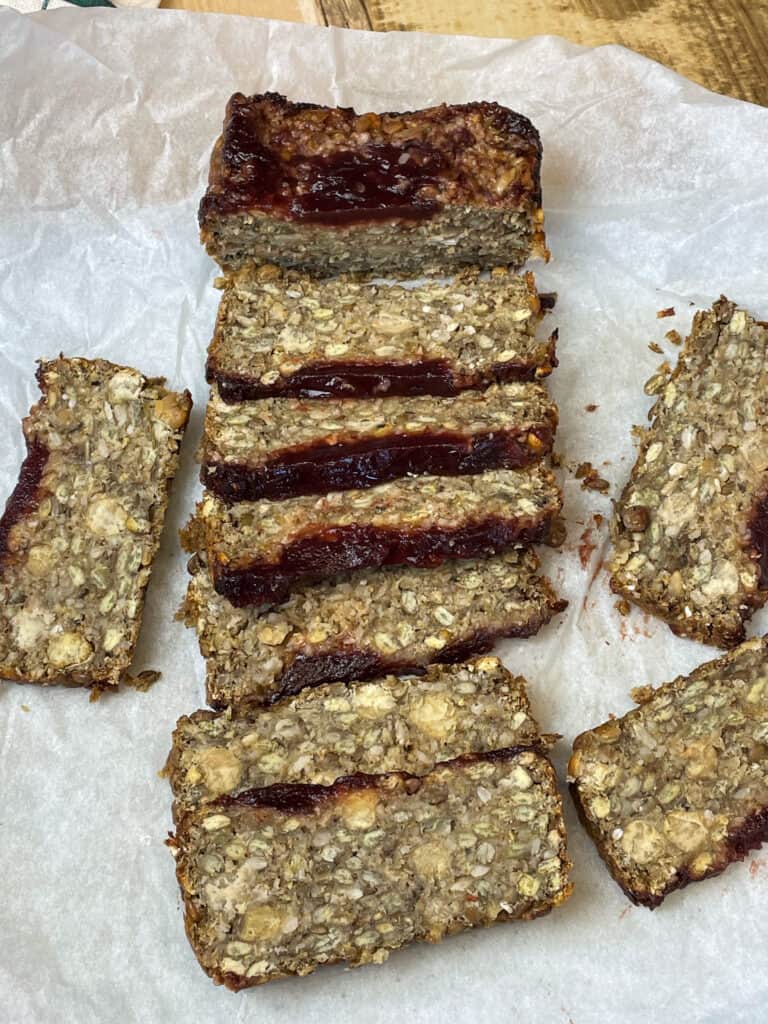 Slices of vegan green lentil, oatmeal, chickpea meatloaf on greaseproof baking paper.