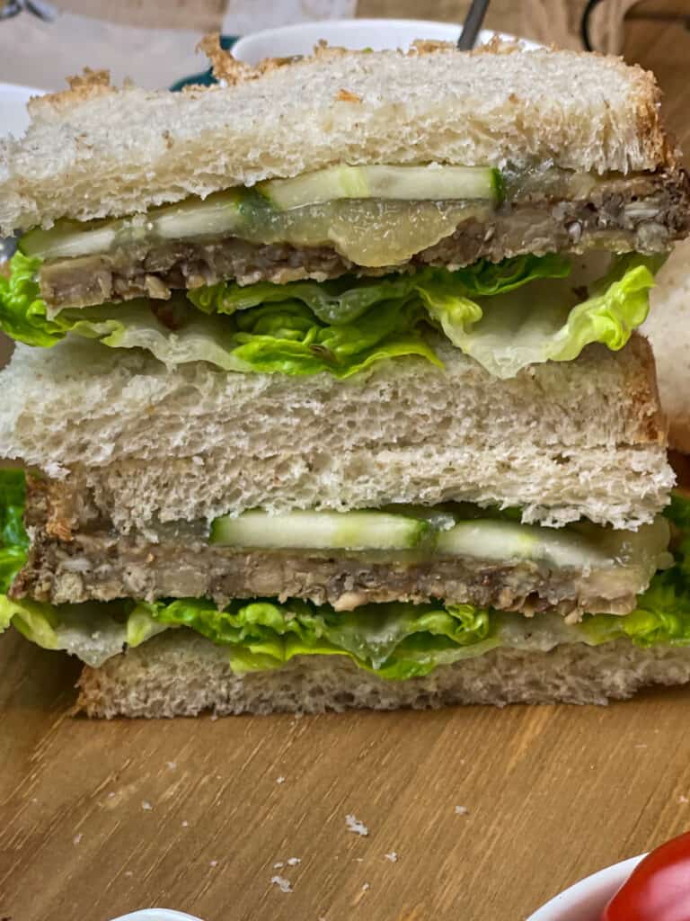 close up of vegan meatloaf sandwich on wooden chopping board.