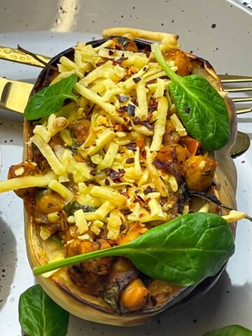A stuffed acorn squash with cheesy topping on a dinner plate.
