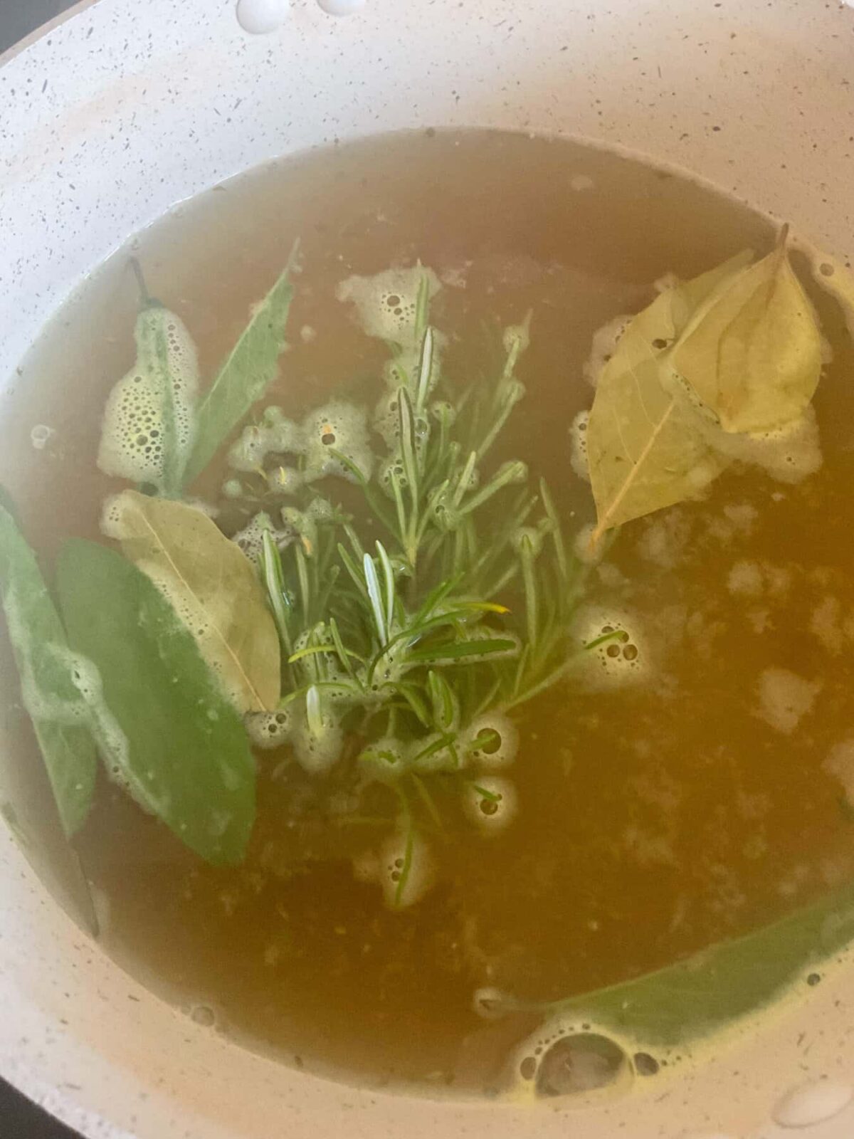 Vegetable stock and herbs added to stew pan with barley.