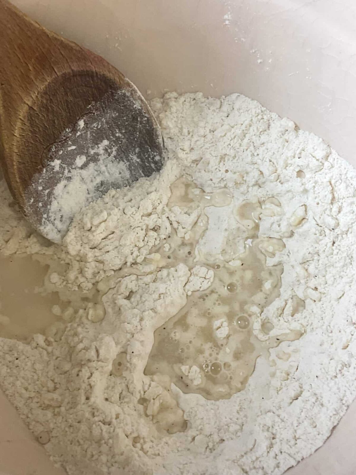 Water added to a bowl with dry ingredients for dumplings.