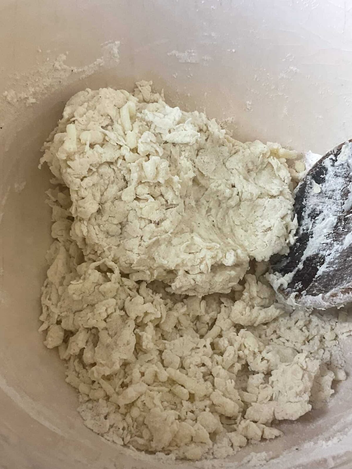Dumpling mixture forming in mixing bowl with wooden spoon.