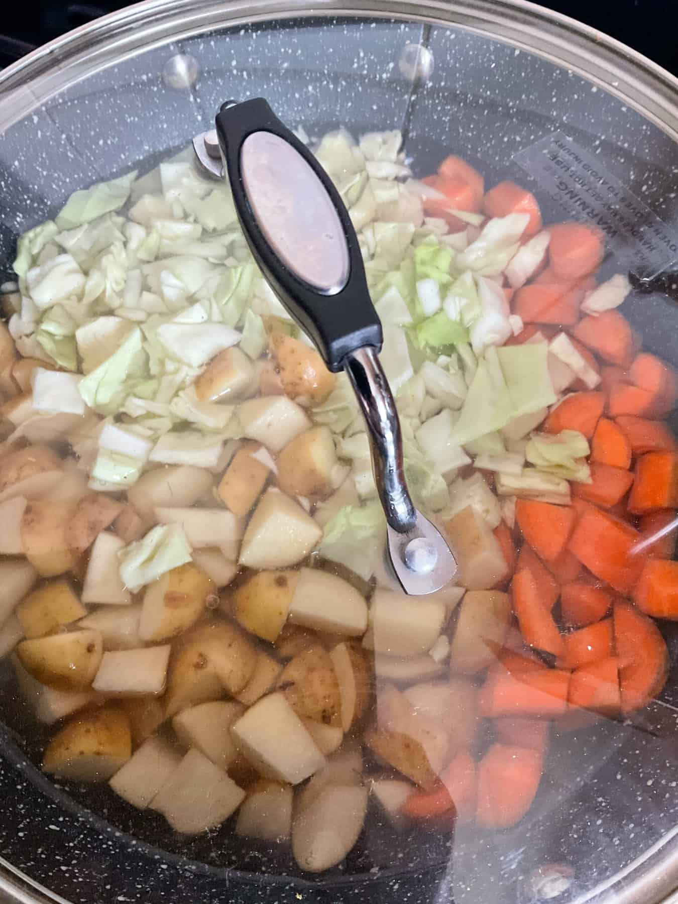 Lid on skillet precooking the veggies.