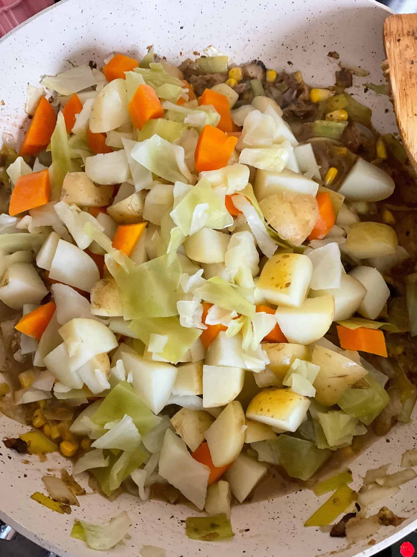 Precooked veggies added to pie filling in pan.