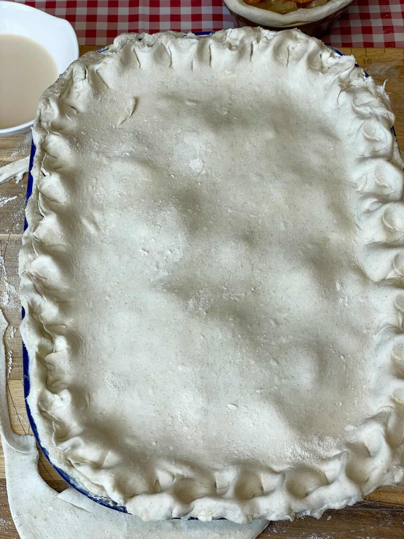 Pastry covering pie dish and the rim in a pressed into a moulded pattern.