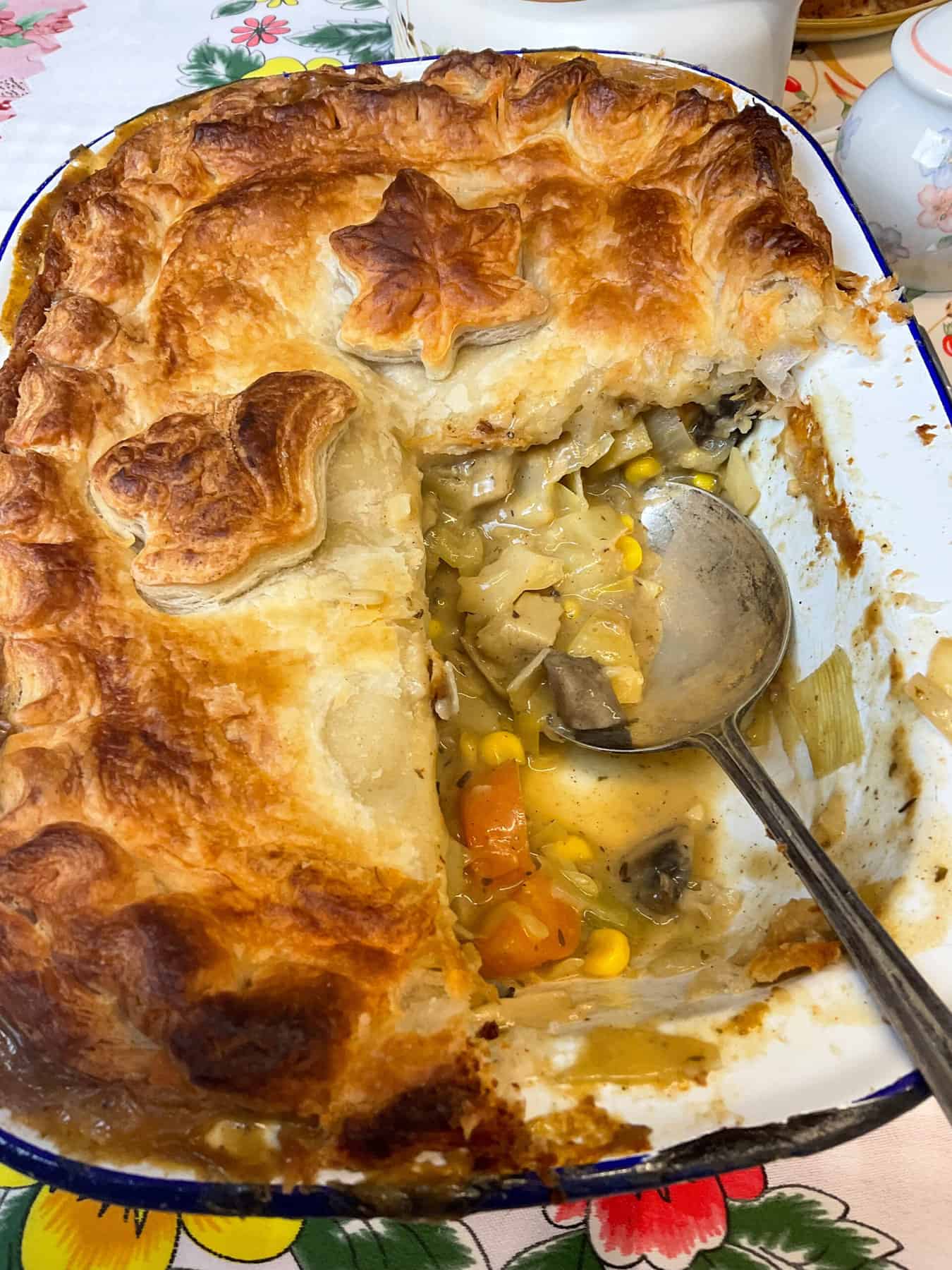 Vegan chicken pie in pie dish with a portion removed and a silver serving spoon in the dish.