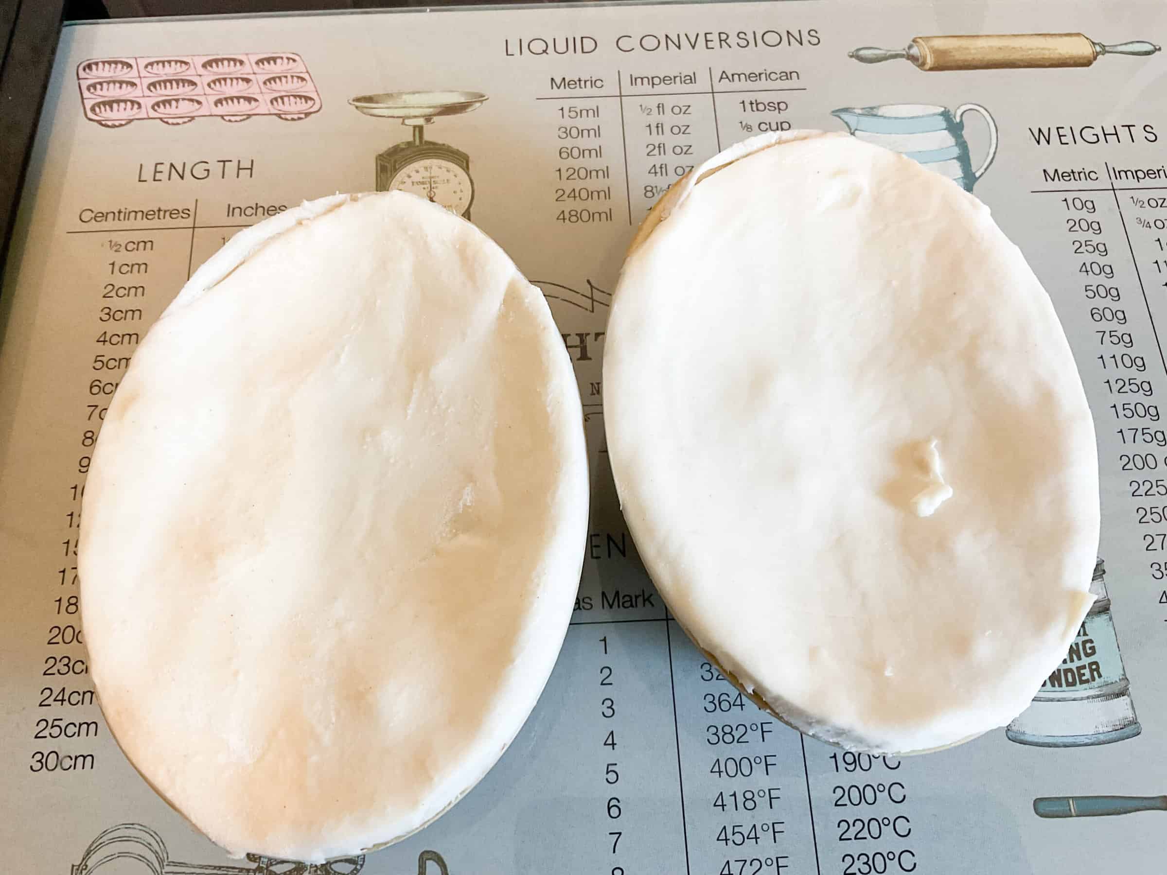 Two individual unbaked pies on a cutting board.