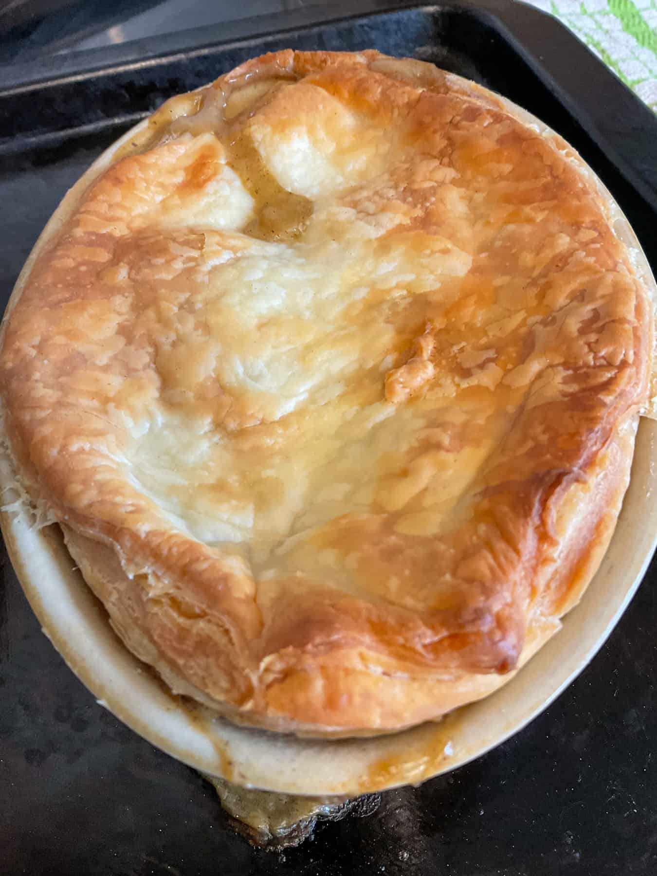 Small individual pie dish with cooked vegan chicken pie on a baking sheet.