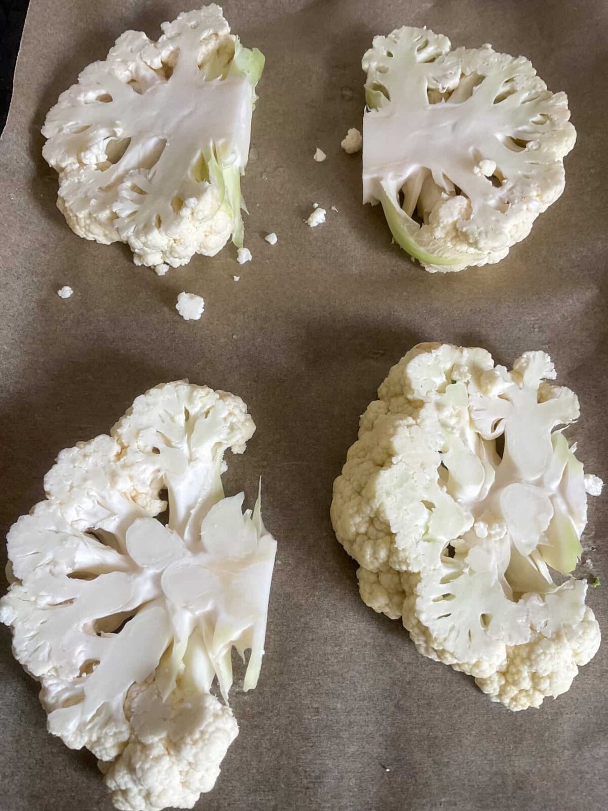 Cauliflower steaks on a baking sheet.