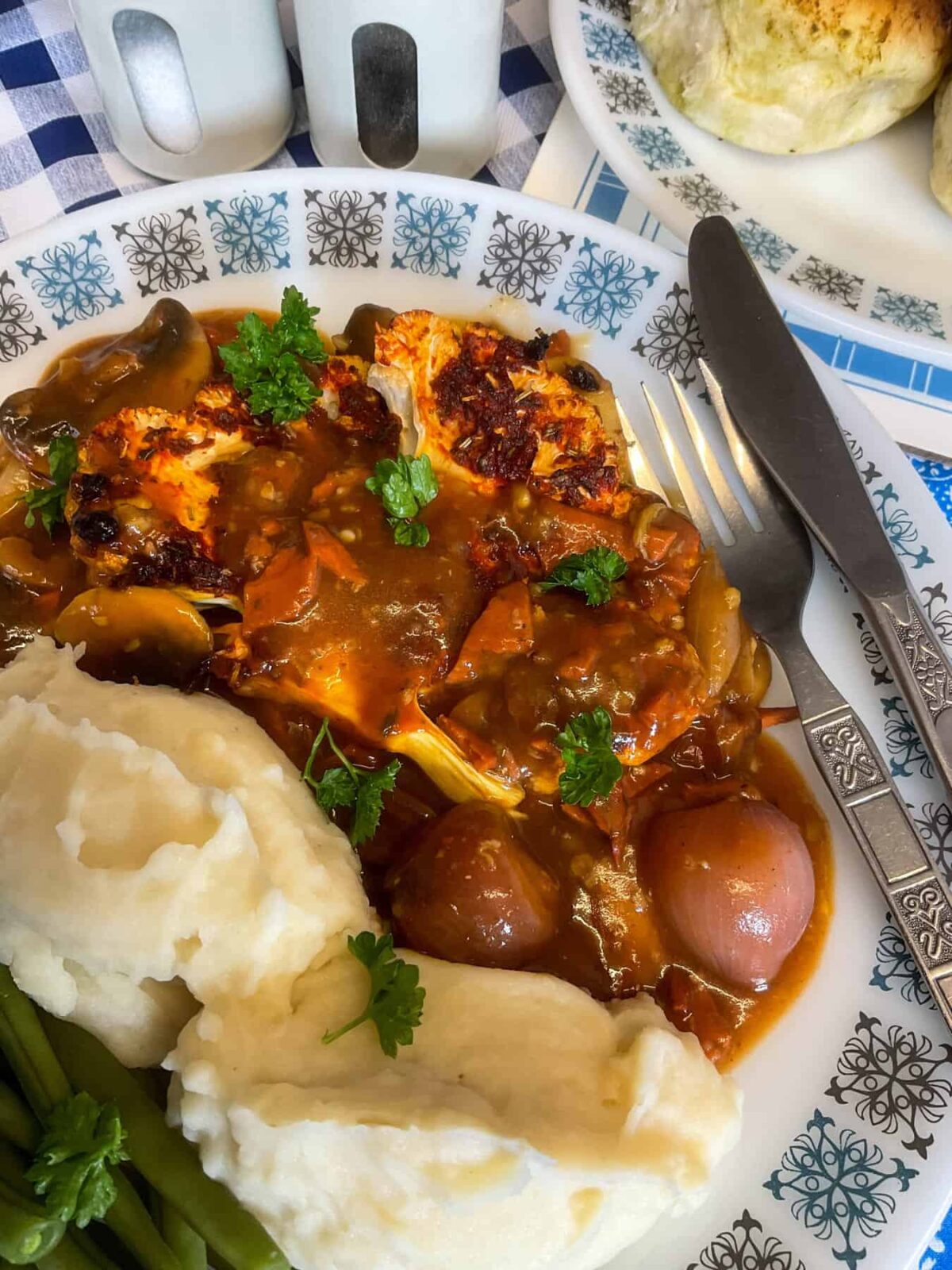 Close up side view of served vegan coq au vin with silver knife and fork.