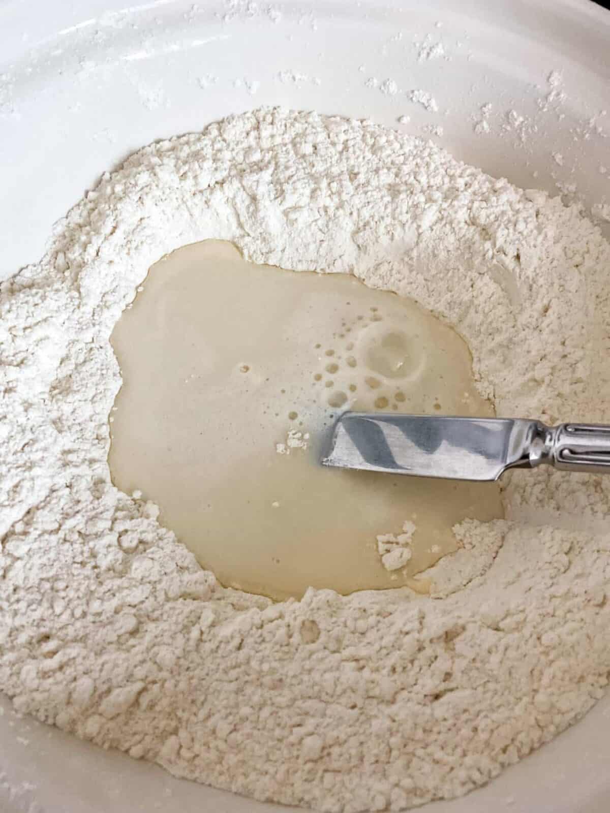 Milk and water added to mixing bowl with cutlery knife.