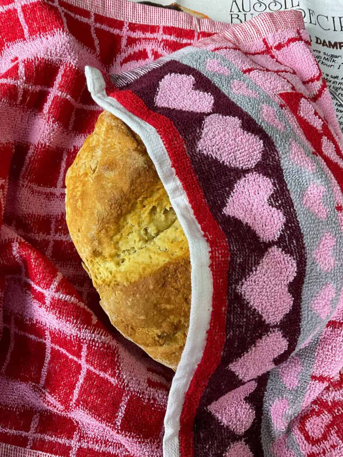 Damper bread wrapped in red and pink coloured tea towel.