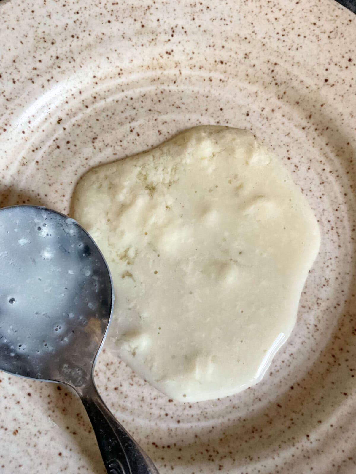 A tablespoon of vegan buttermilk on a saucer to show the curdled milk.