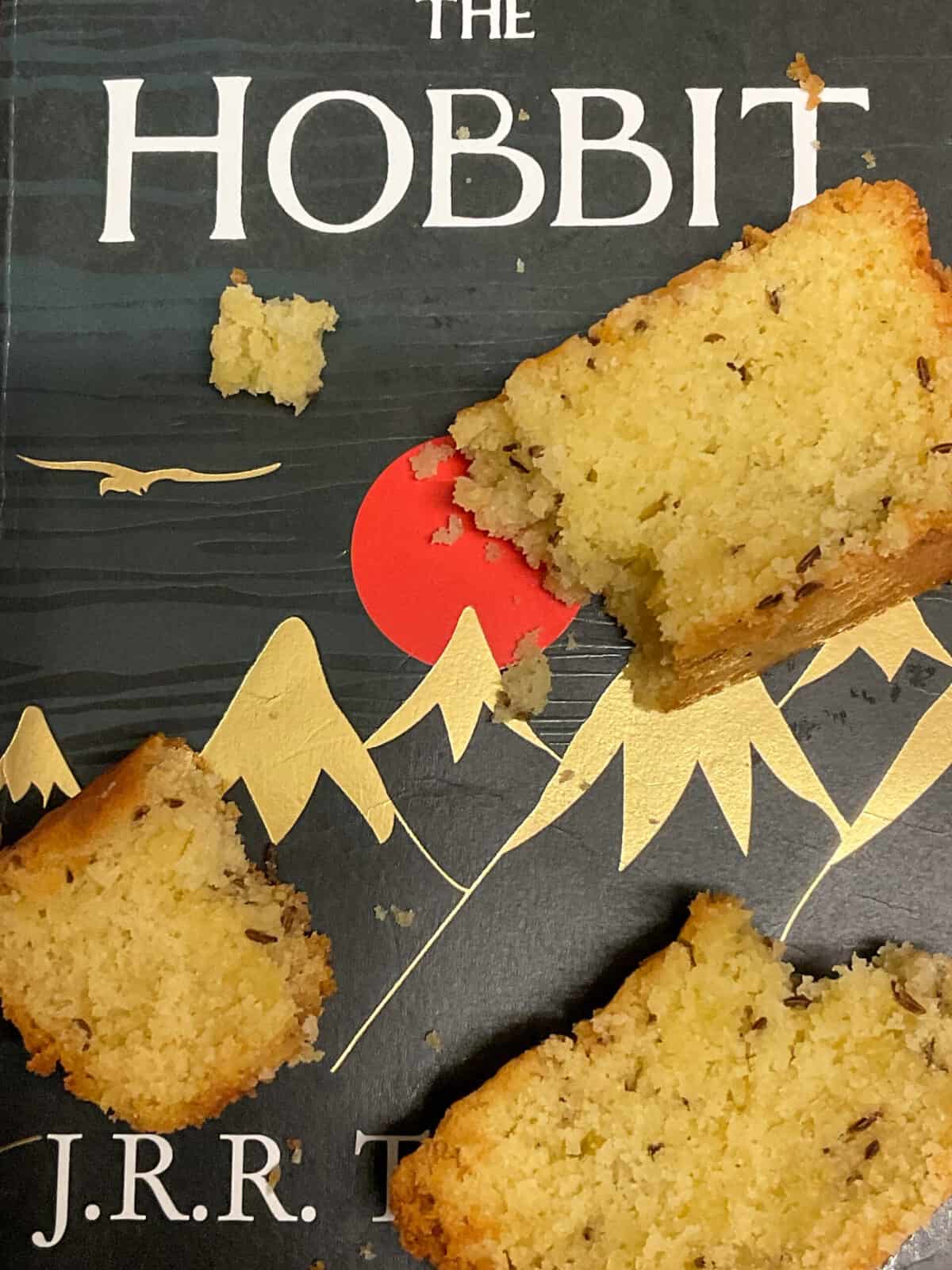 A close up image of The Hobbit book with a black cover and mountain and eagle images, bits of seed cake over the book.