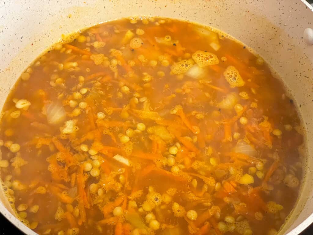 Vegetable stock added to lentil mix in pot and brought to the boil to cook.