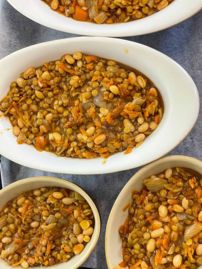 Lentil bean pie filling added to individual pie dishes s two white and two brown pie dishes.