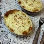 two small pie dishes with doily placemat/ featured image. lentil and bean pie filling, brown handled forks to side, white