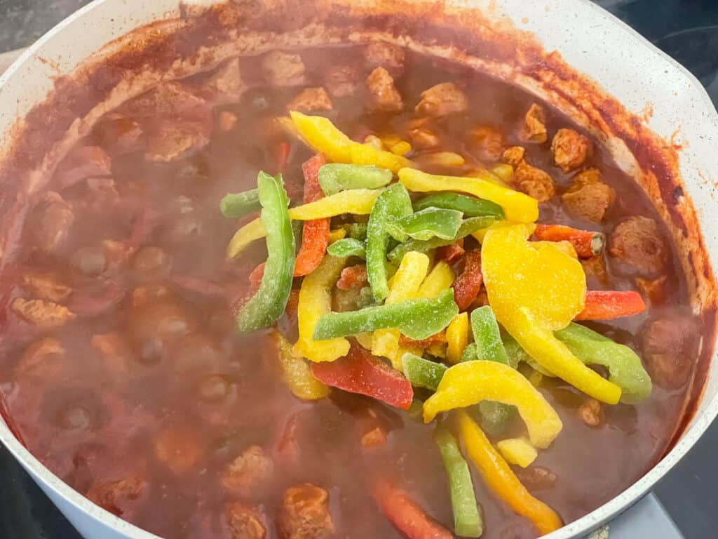 mixed bell peppers added to cooking Hungarian goulash in pot.