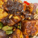 sweet peanut tofu served with stir fry veggies and noodles in white bowl, close up photo, featured image